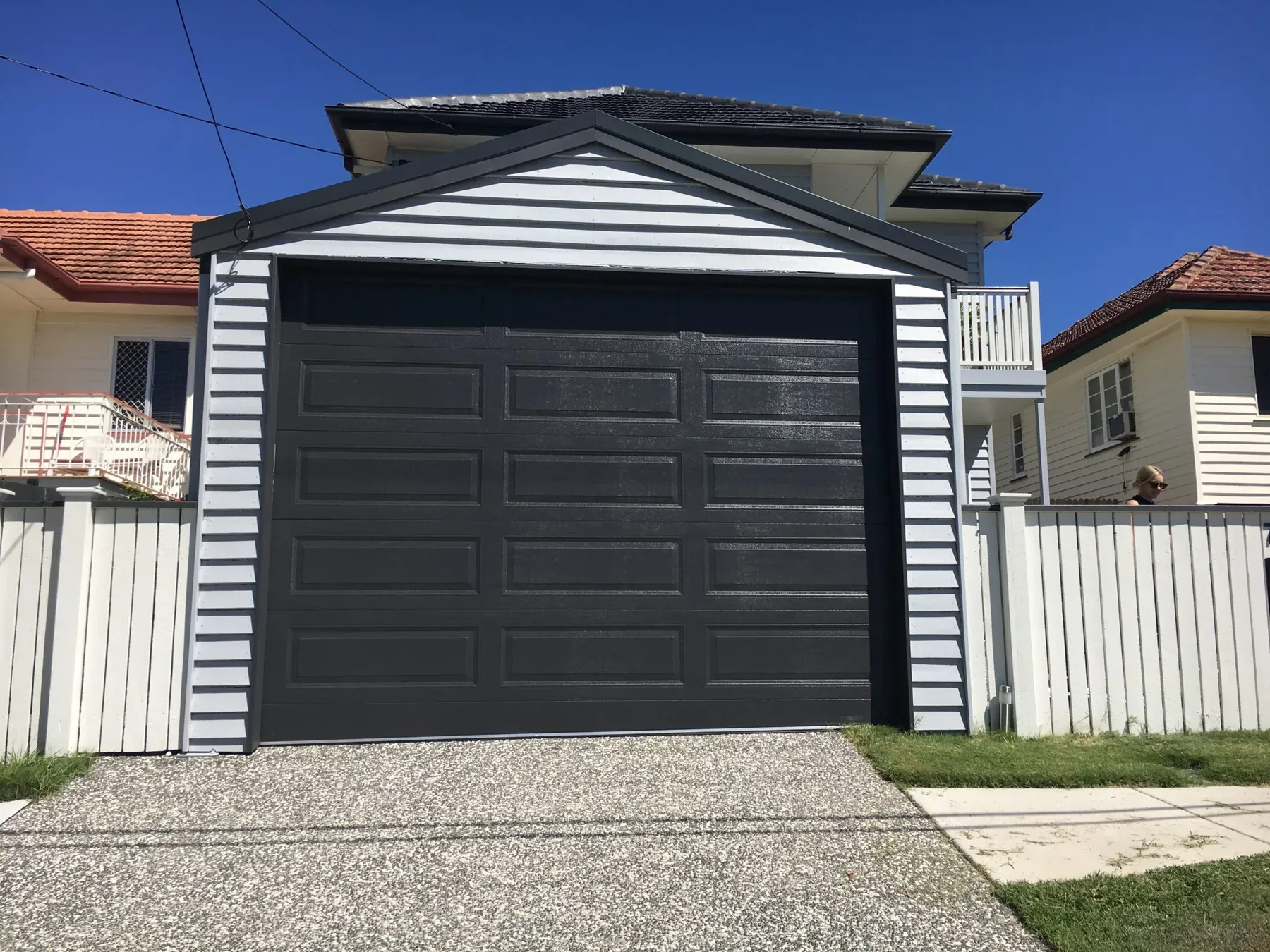 Enclosed gable garage with weatherboard walls and a dark panel door