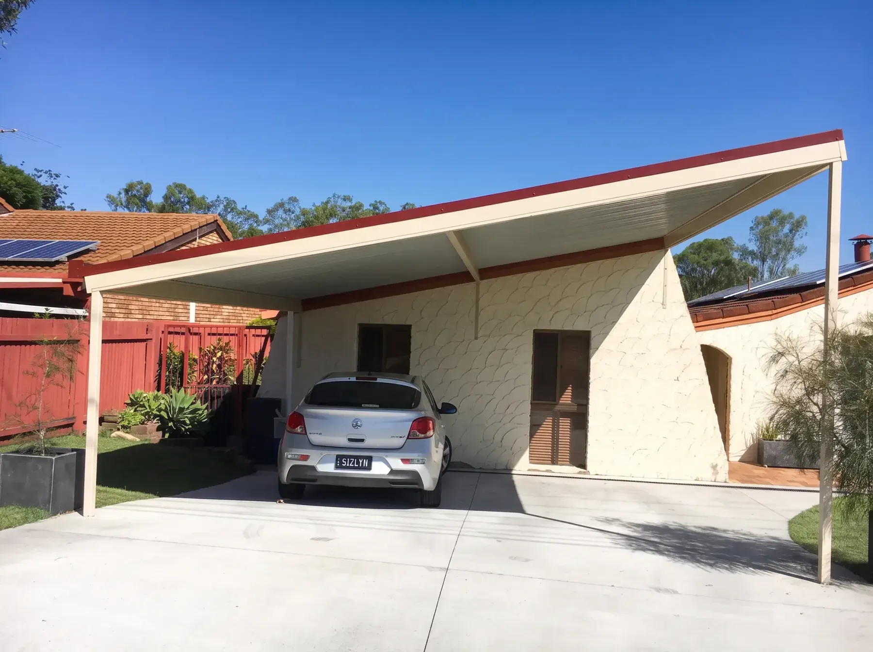 Skillion carport over a car beside a rendered wall