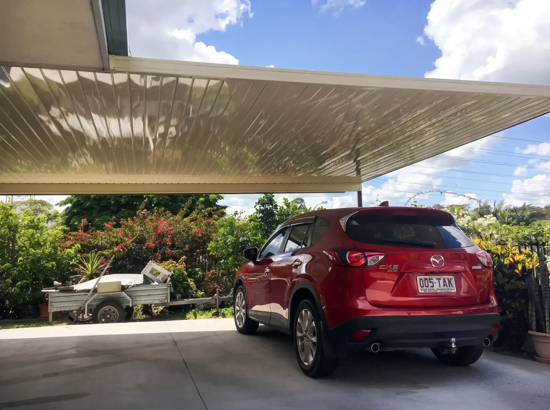 Carport roof over a red SUV, seen from beside the driveway