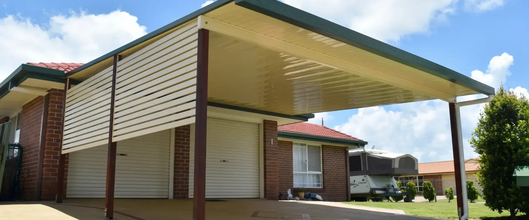 Carport with a slatted side screen beside a brick home