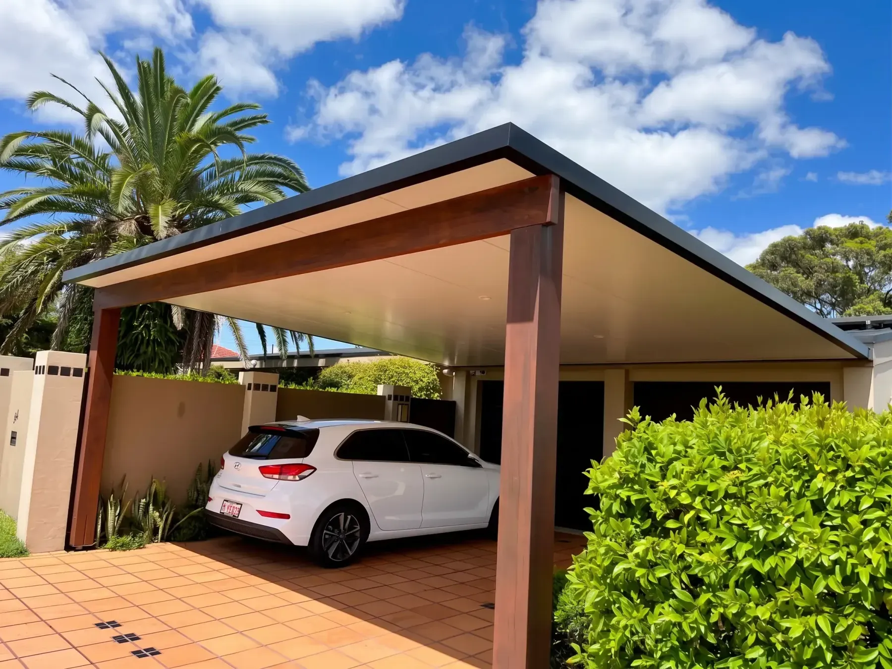Gable carport with timber-look posts and a panel ceiling over a tiled driveway