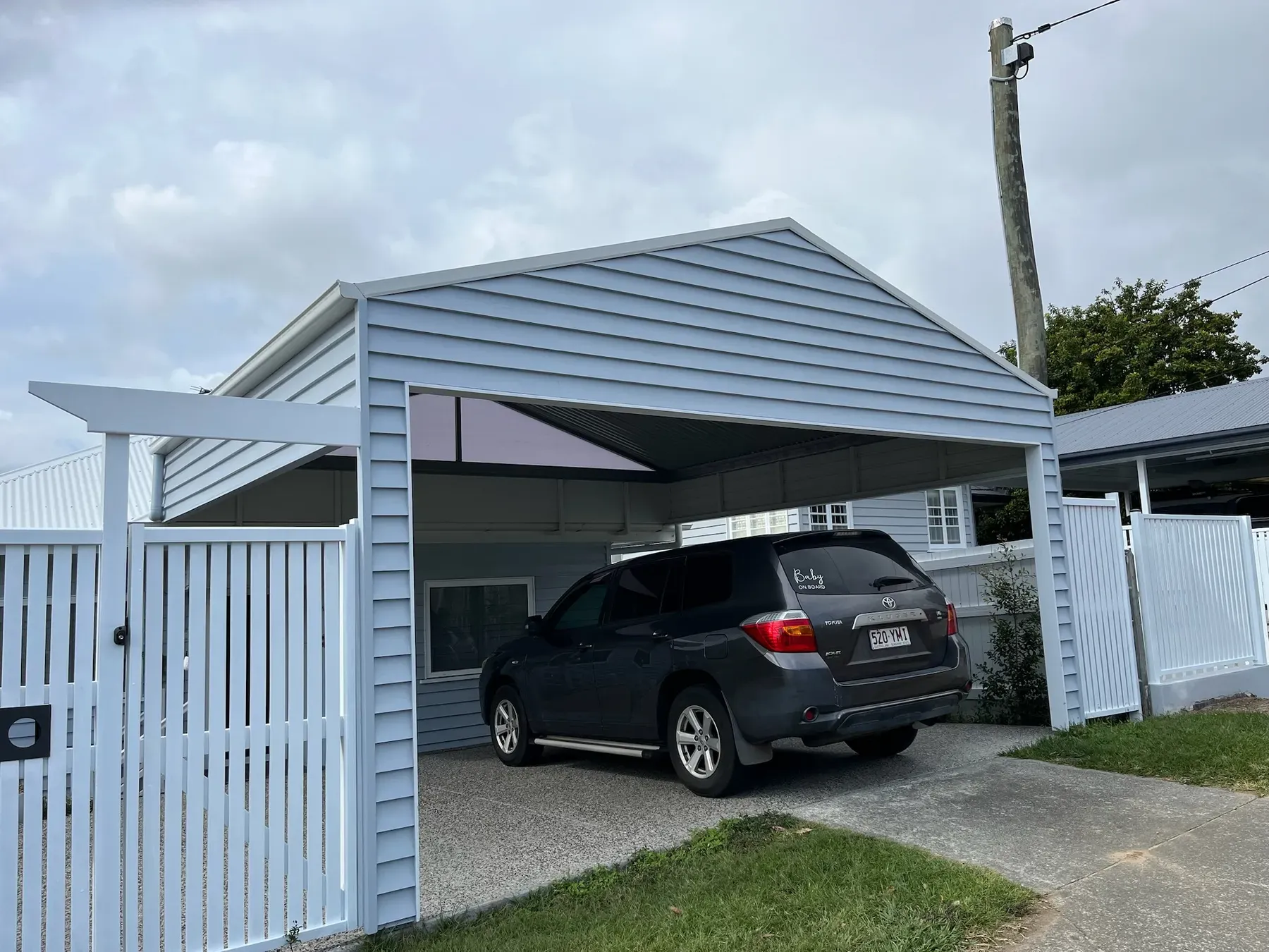 Gable carport with weatherboard ends and gate over a car