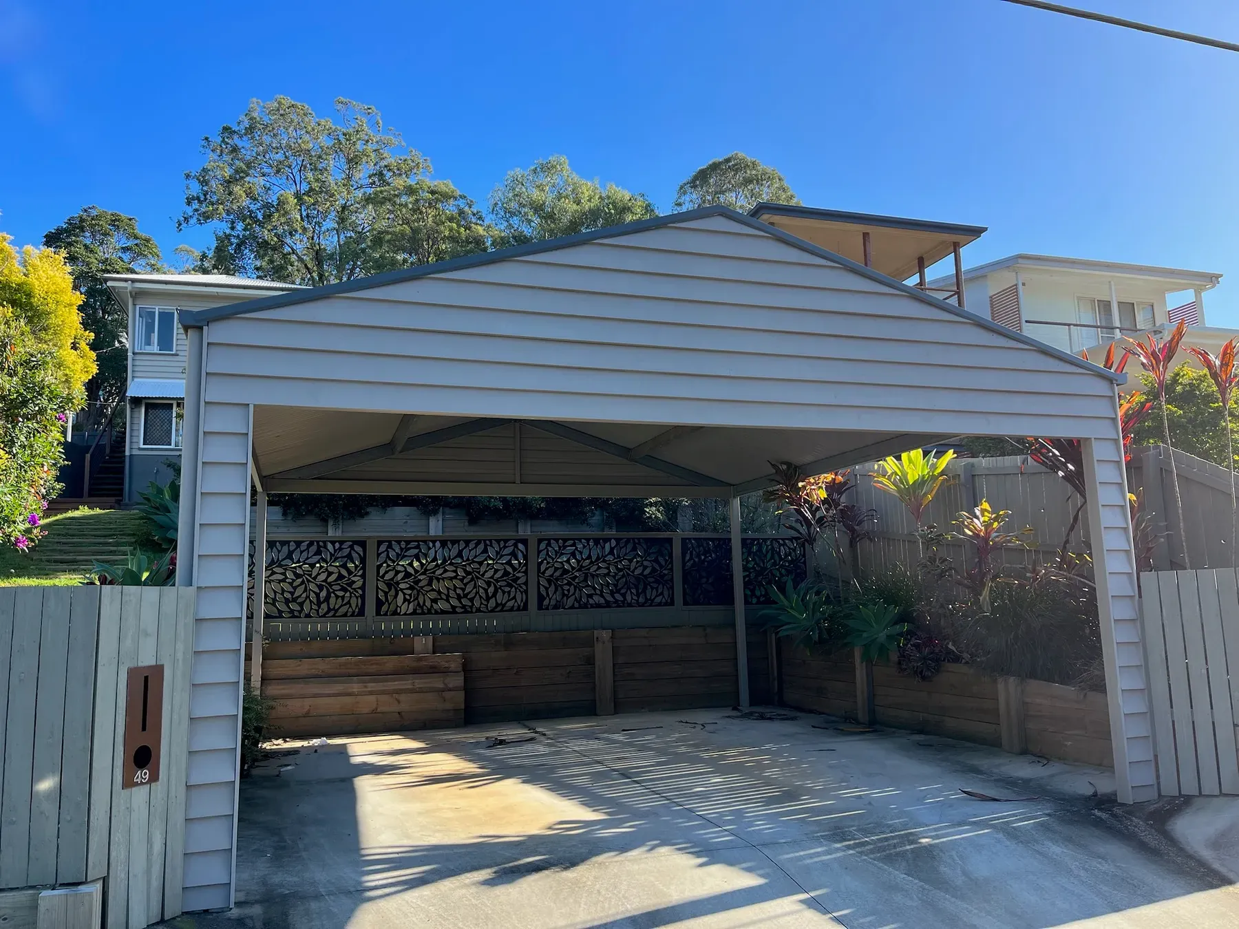 Gable carport with a timber screen at the back over a concrete driveway