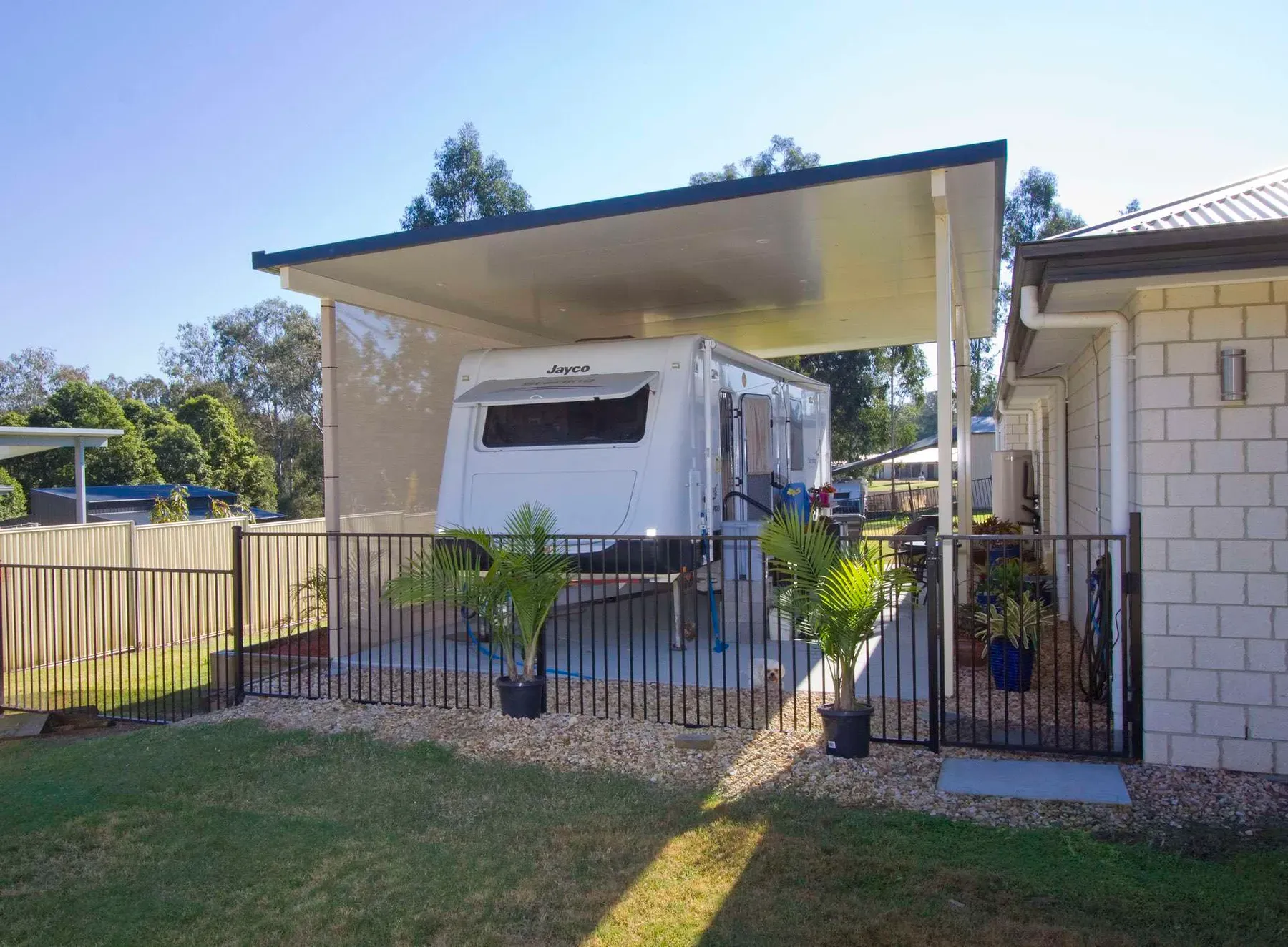 High-clearance carport over a caravan beside a lawn