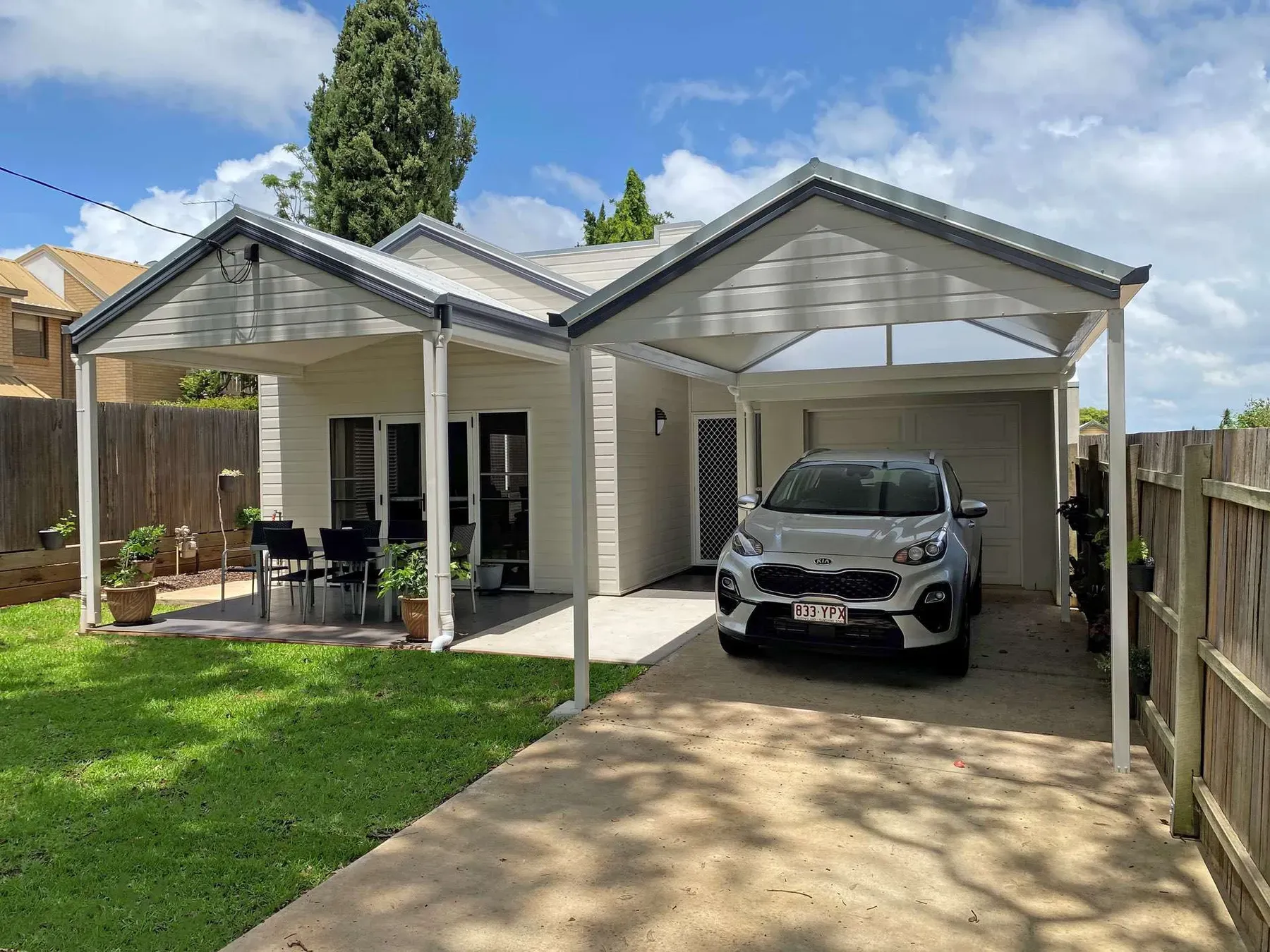 Twin gable roofs over a patio and a carport beside a weatherboard home
