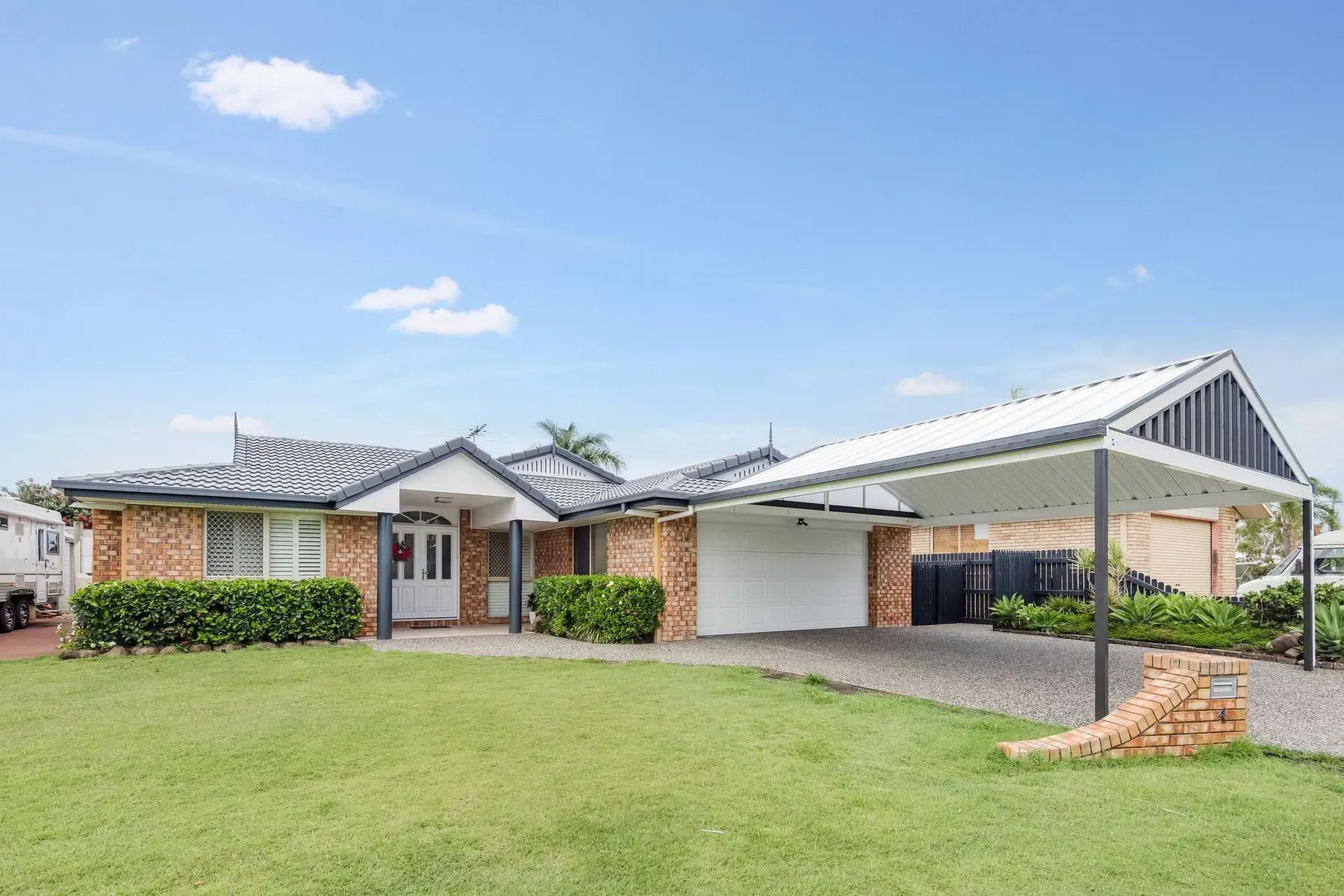 Gable carport beside a brick home with a wide front lawn