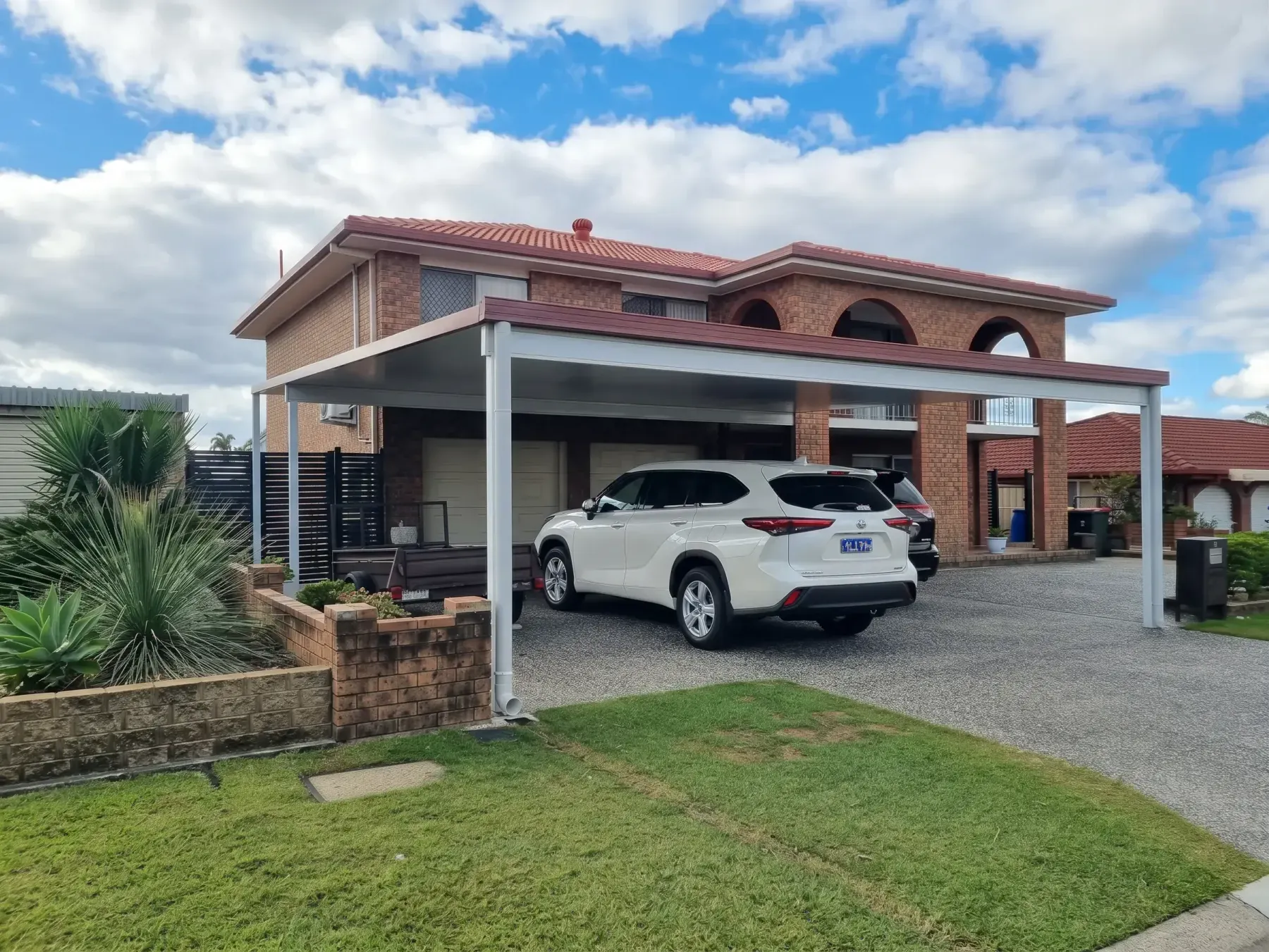 Carport over an SUV beside a two-storey brick home
