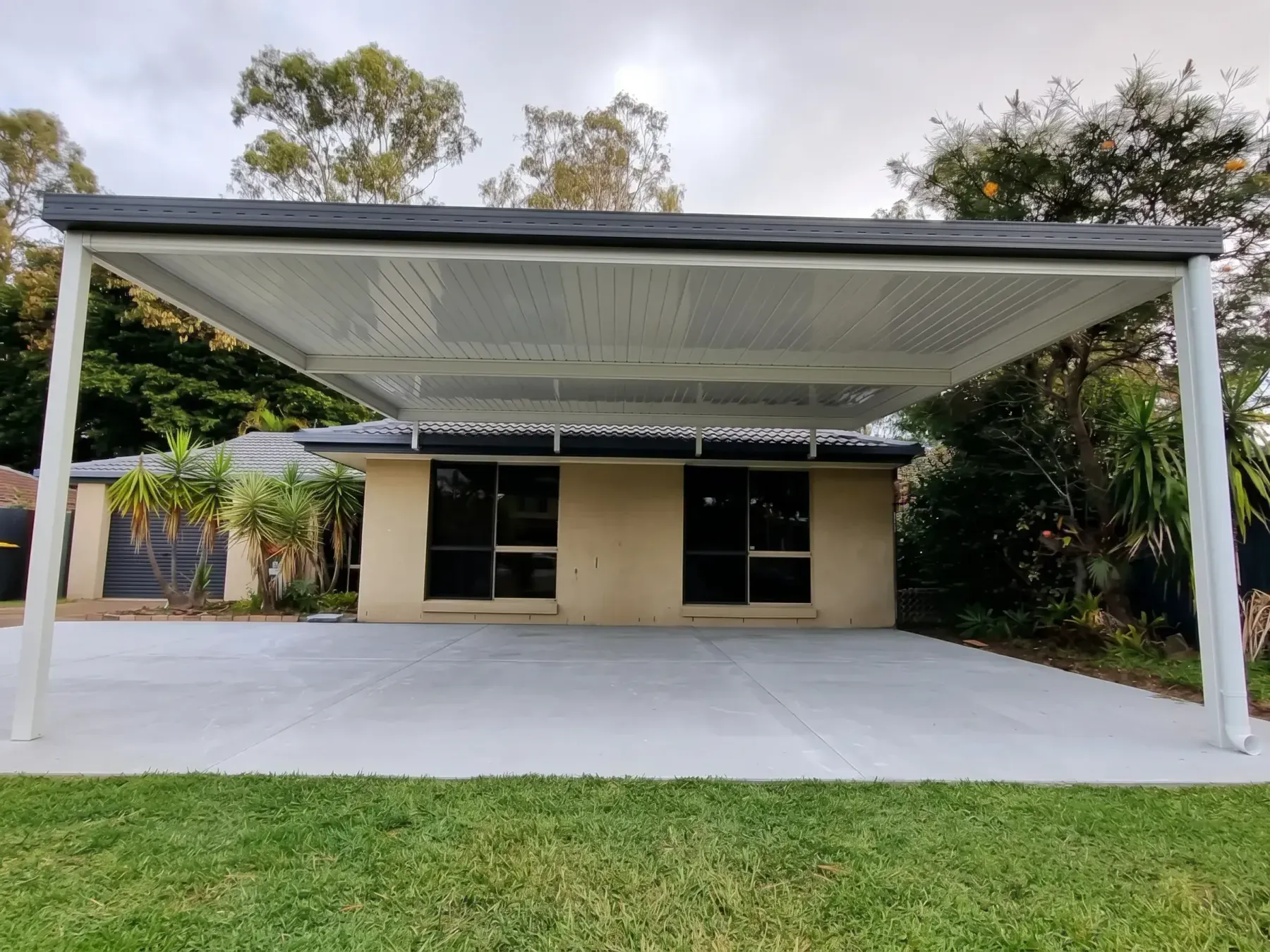 Carport over a new concrete slab beside a brick home