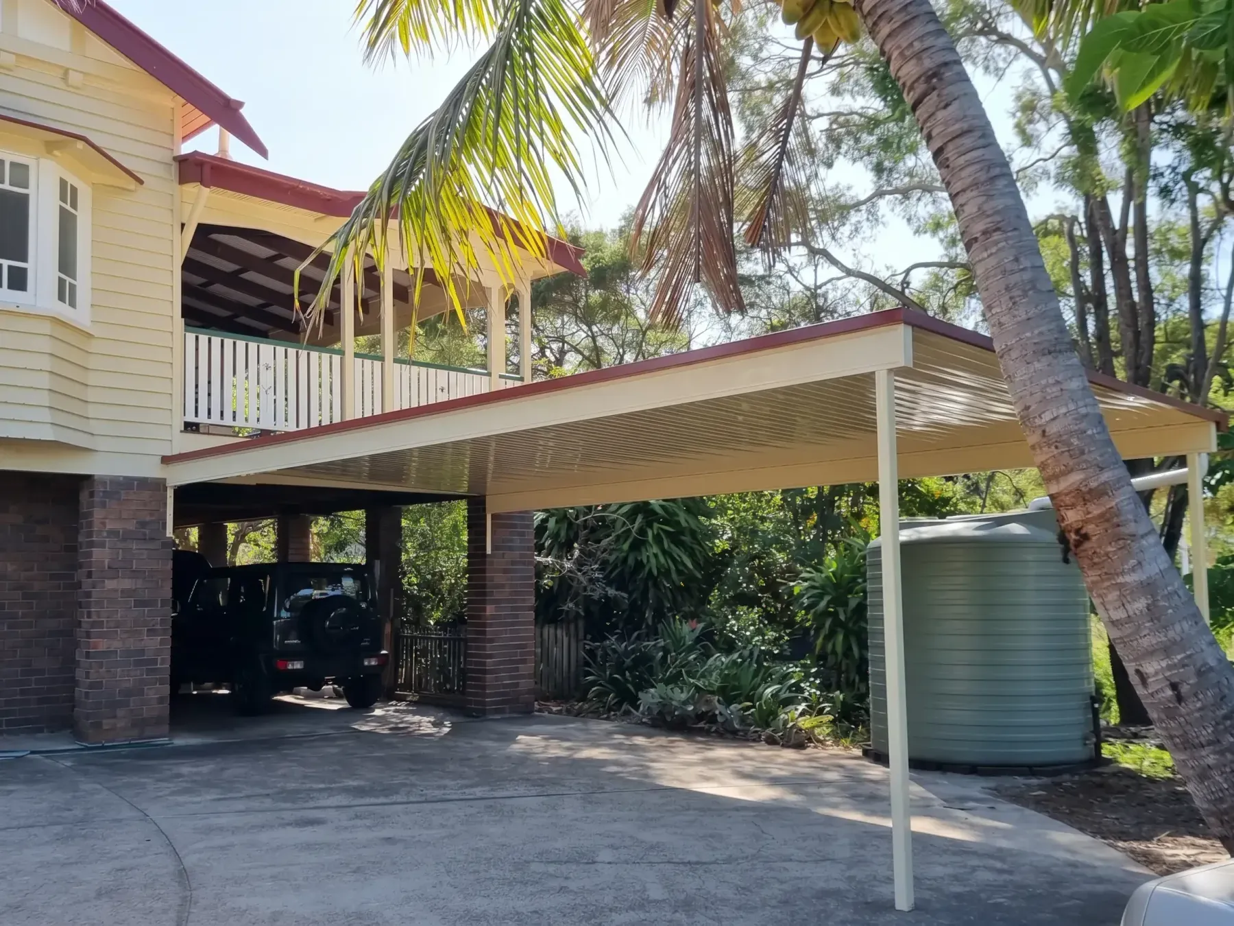 Carport beside a raised Queenslander with a water tank