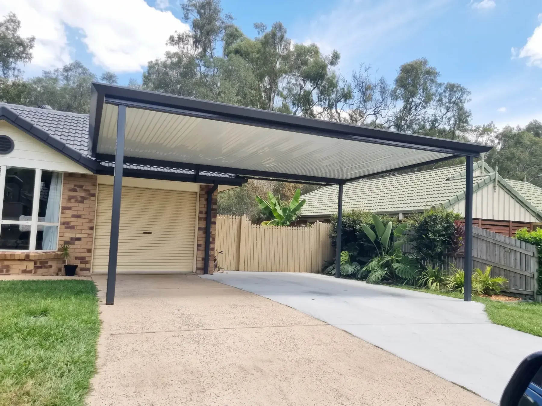 Dark-framed flat roof carport over a double driveway