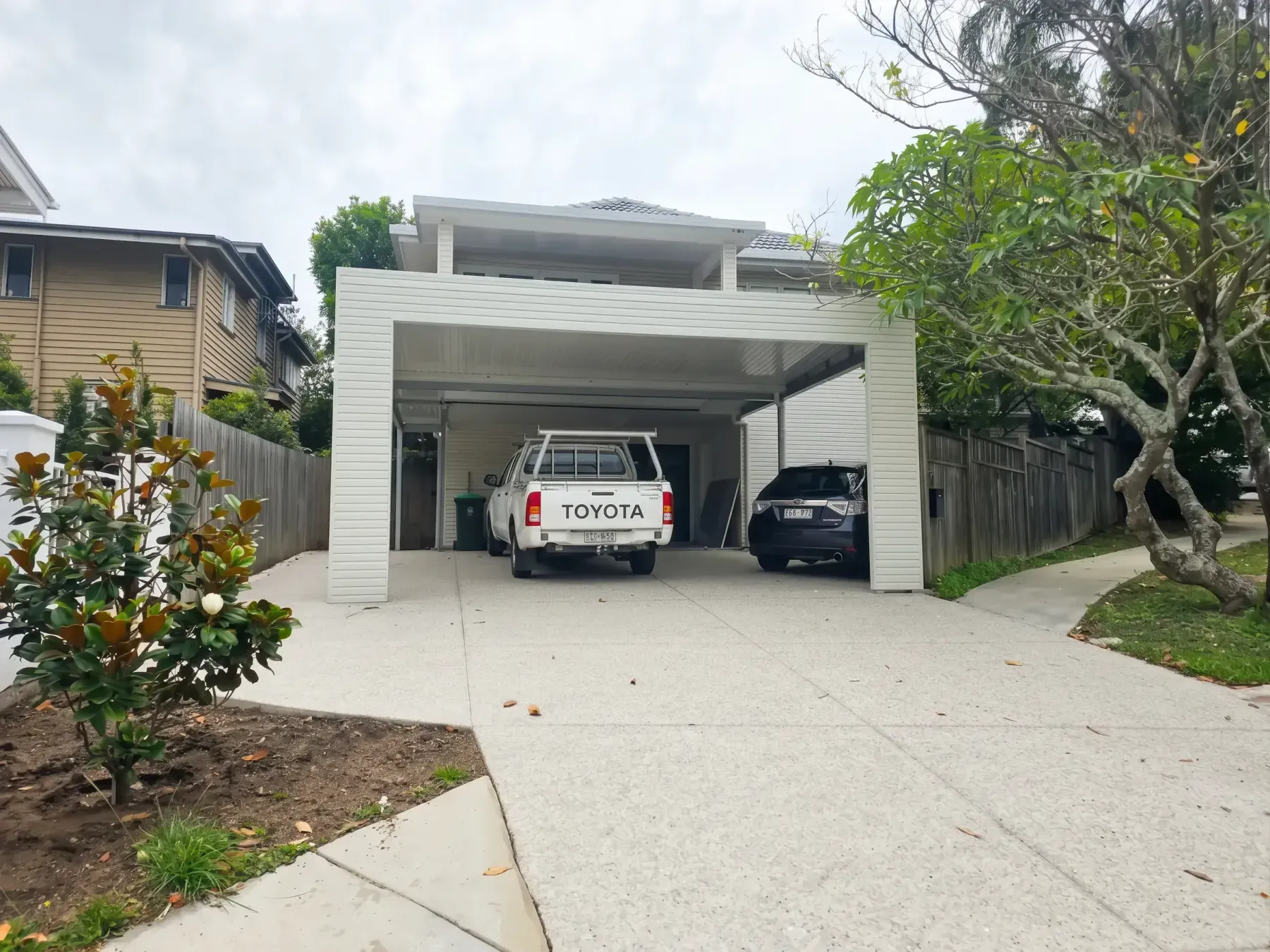 Enclosed double carport over a ute and a car on a wide driveway
