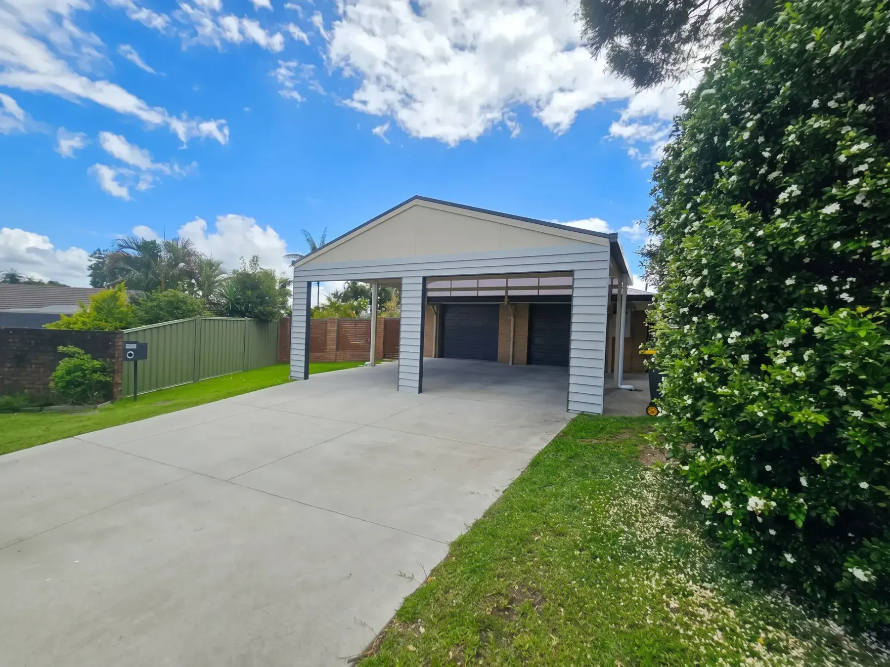 Gable carport with weatherboard ends at the end of a long driveway