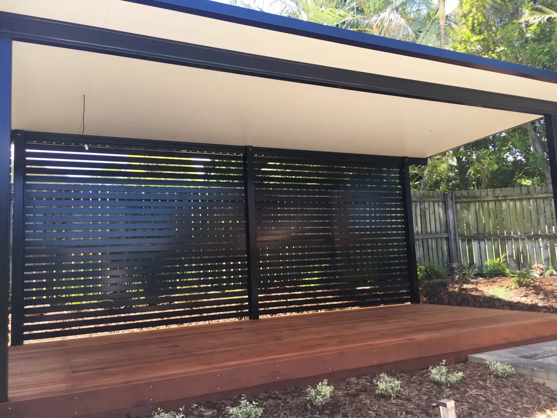 Steel-framed deck with a slatted privacy screen under a patio roof