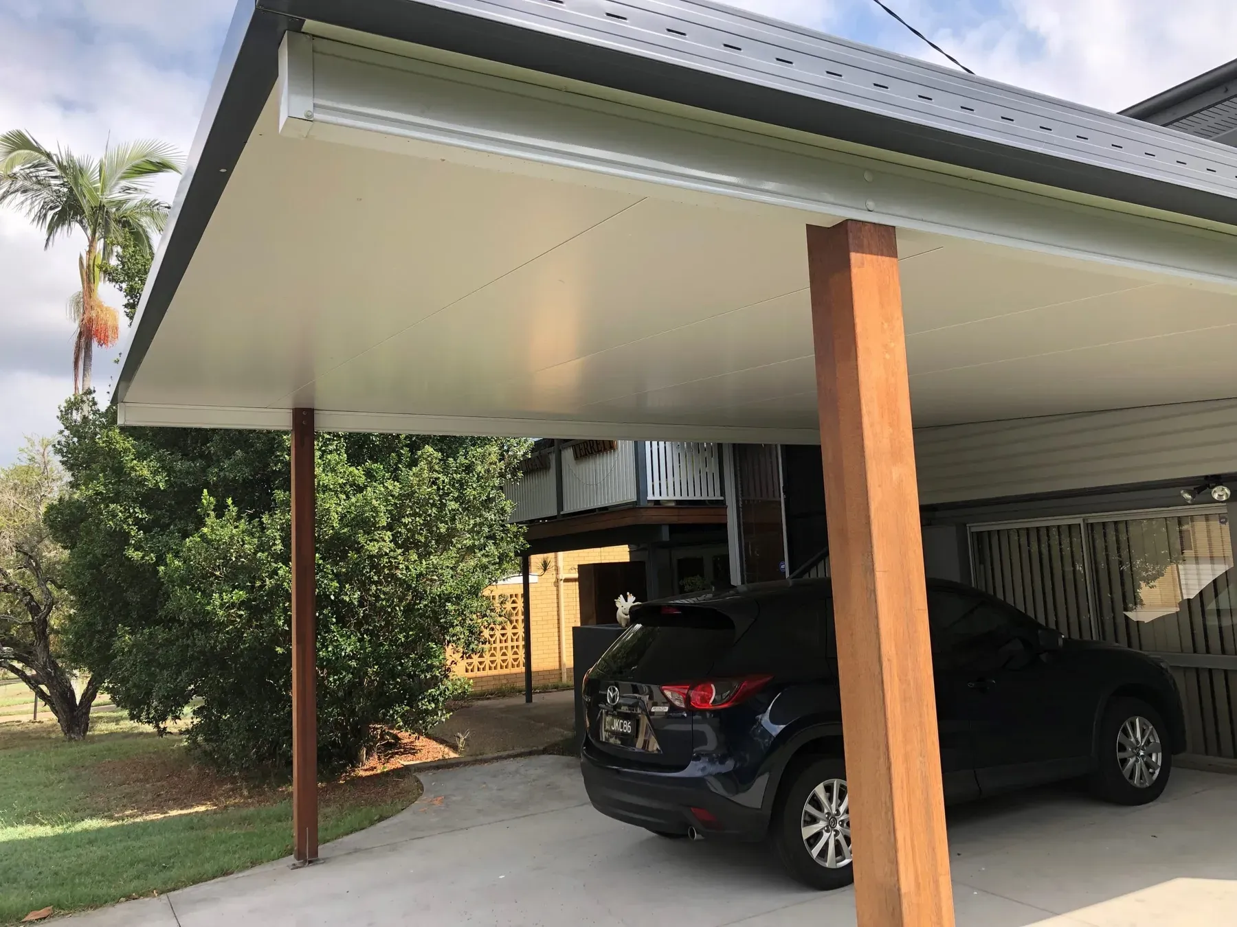 Carport with timber posts beside a garden, seen from the side