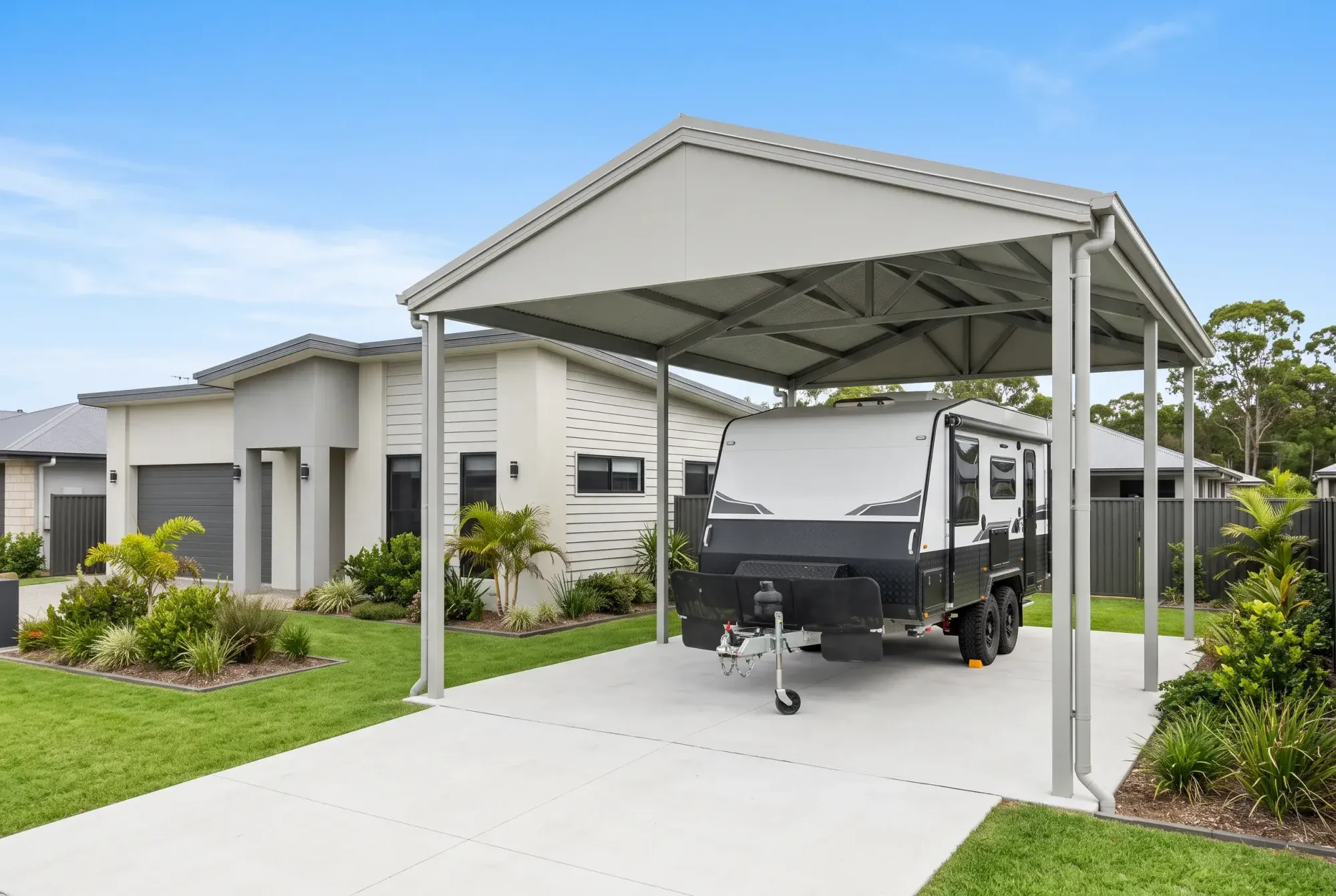 Tall gable carport over a caravan beside a home