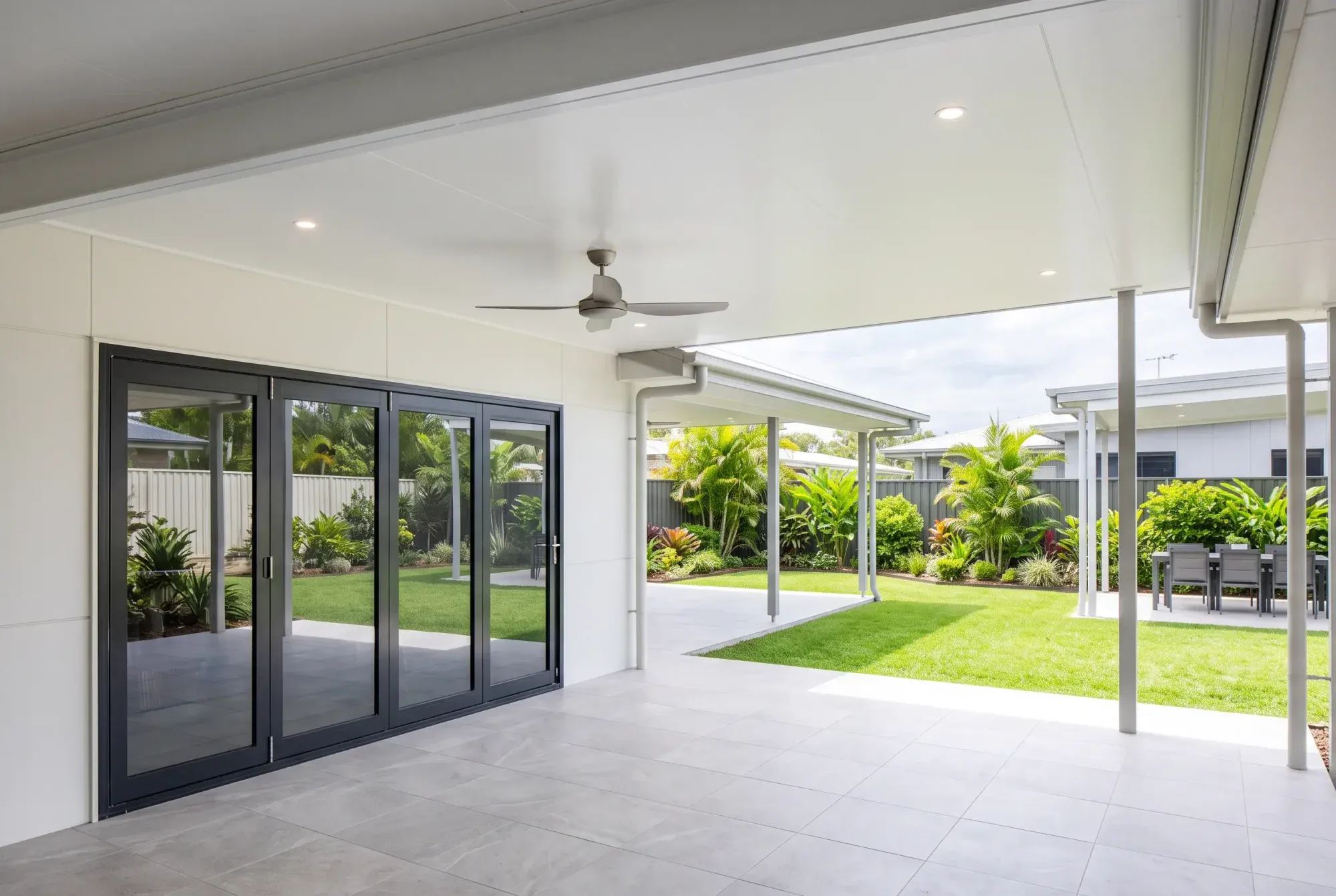 Looking up at a smooth insulated patio ceiling with downlights and a fan
