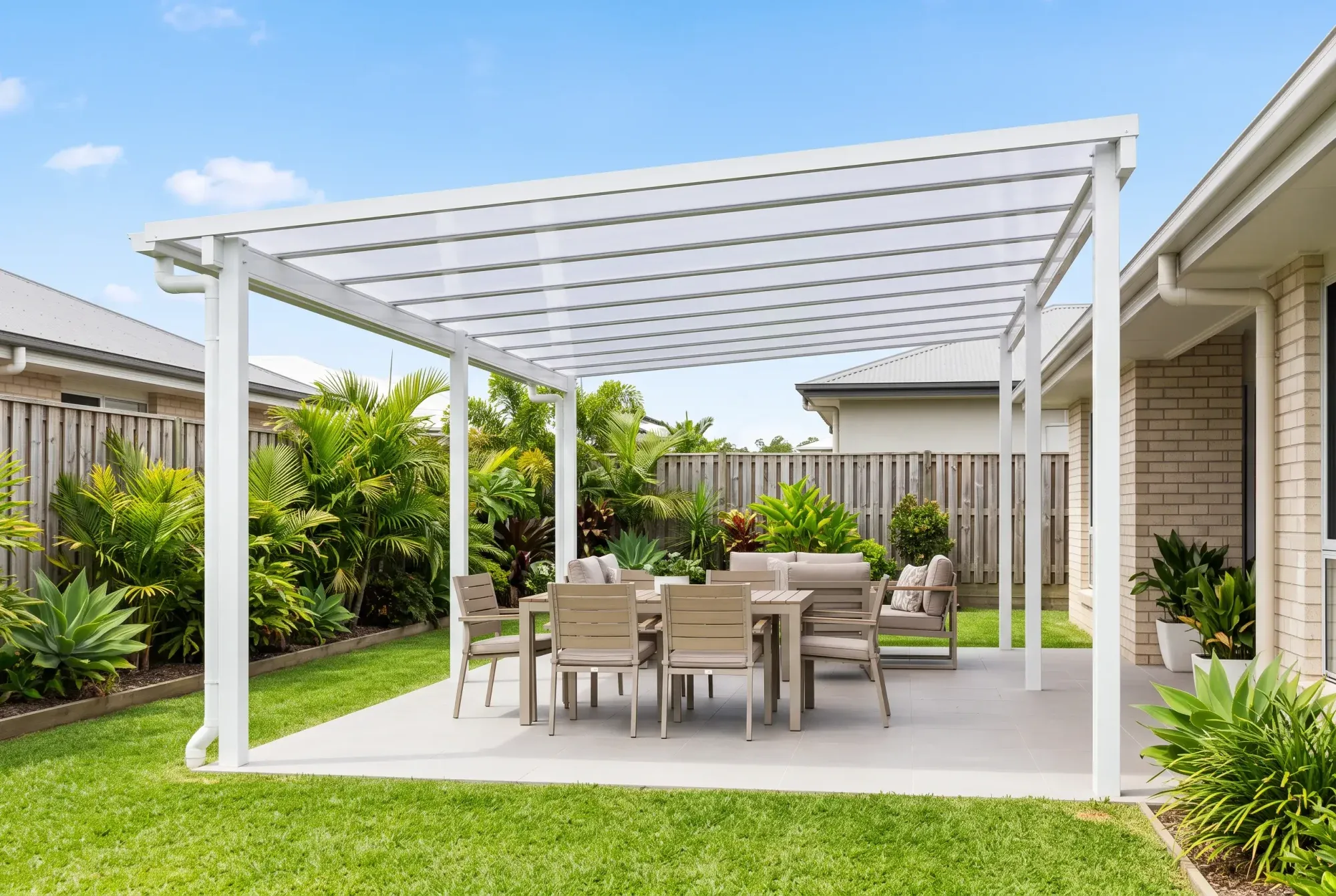 Freestanding steel pergola with a clear polycarbonate roof over a paved dining area