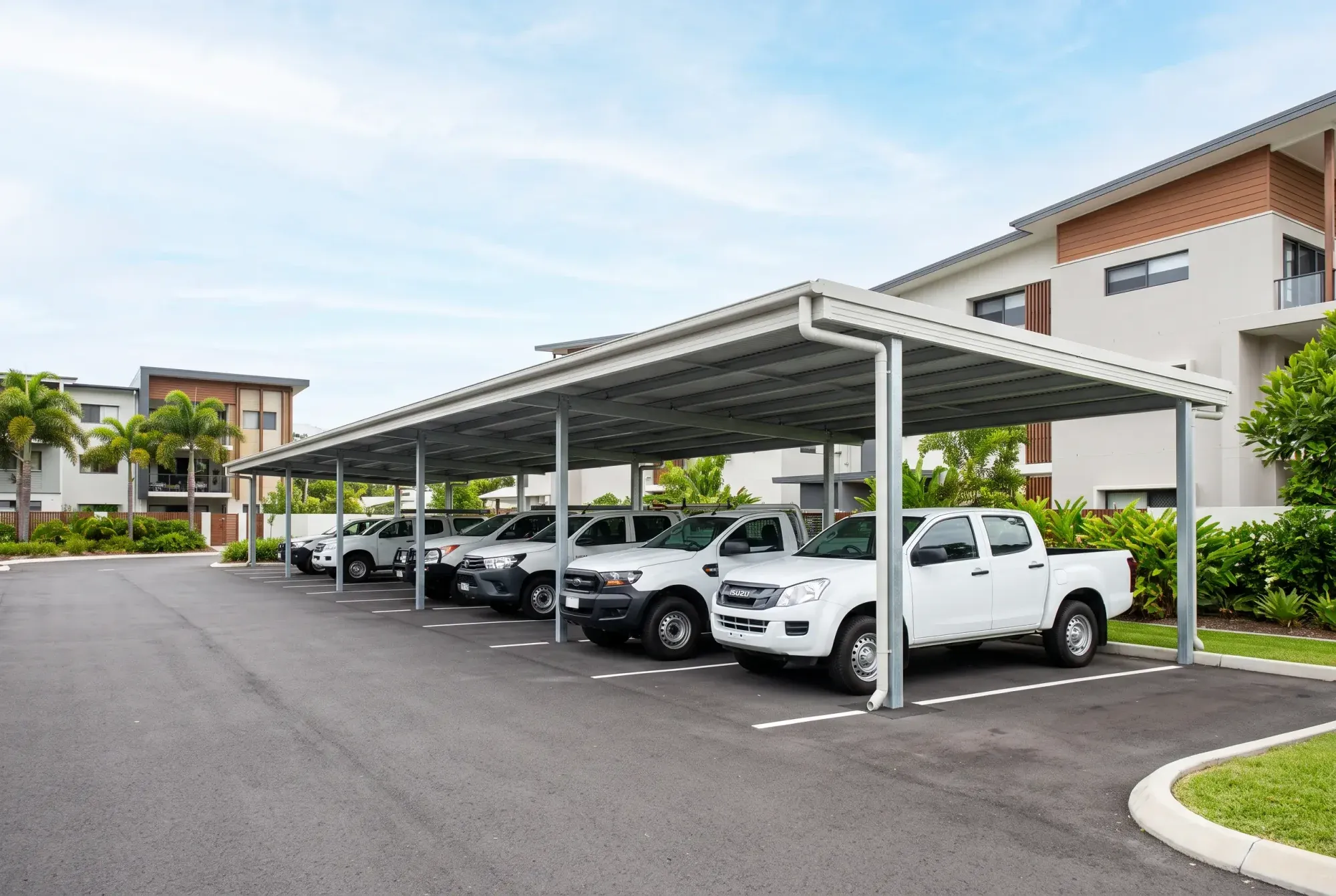 Multi-bay steel carport over a row of work vehicles