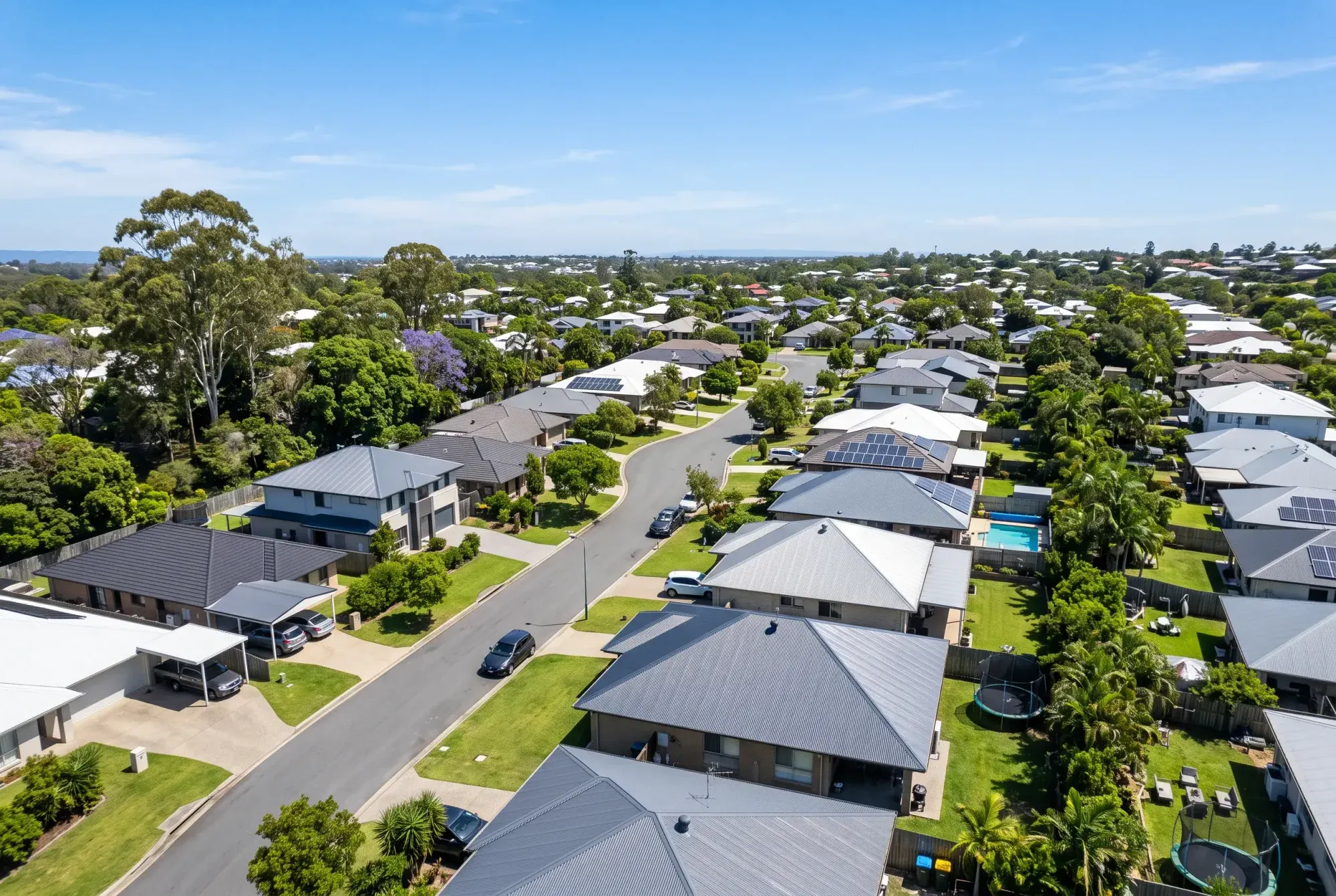 Elevated view over a leafy Brisbane suburb of homes with carports and patios