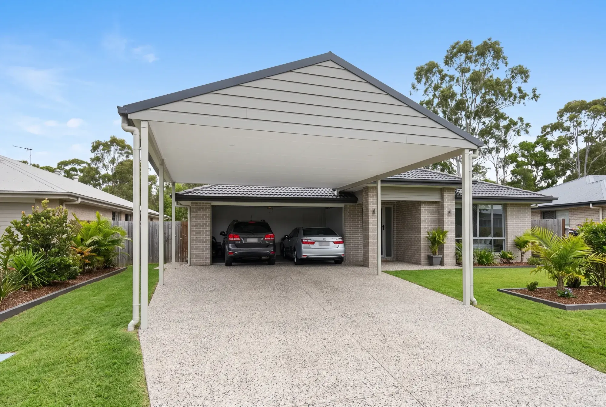 Gable carport over a double garage driveway, brick home behind