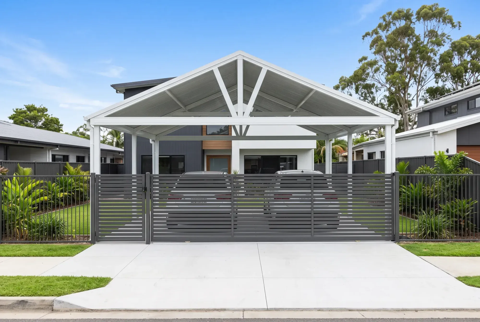 Gable carport behind a slatted driveway gate