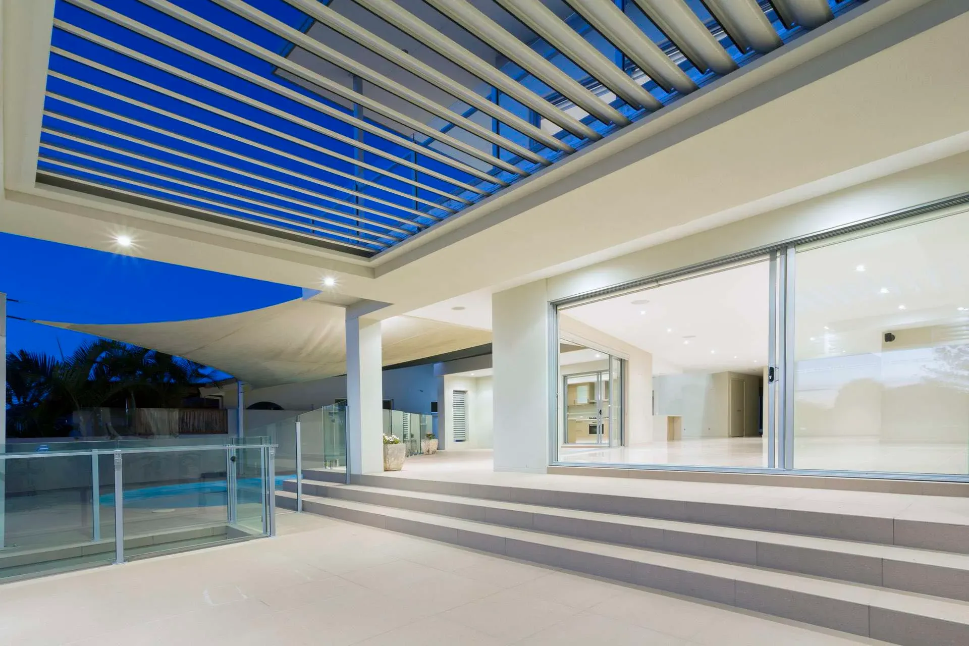 Modern white alfresco with a louvred roof beside a swimming pool